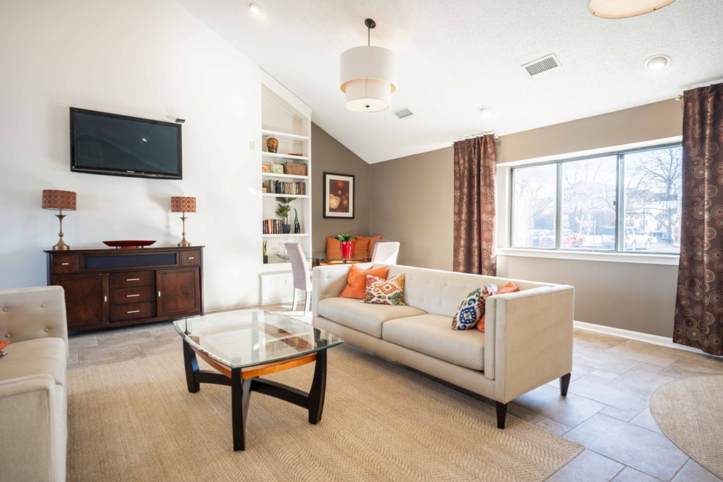 A living room with a white couch and a glass coffee table.