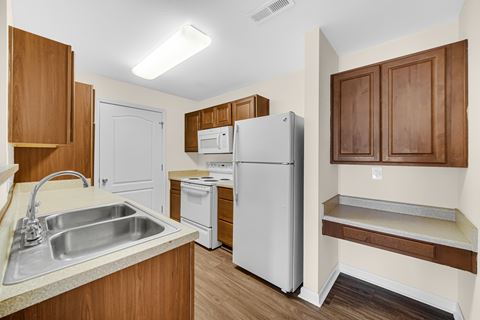 a kitchen with a sink and refrigerator and wooden cabinets