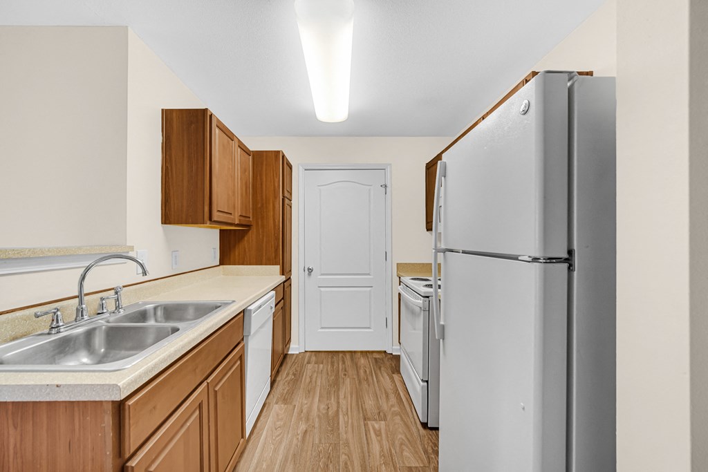 an empty kitchen with a refrigerator and a sink at Brickshire Apartments in Merrillville, IN 46410