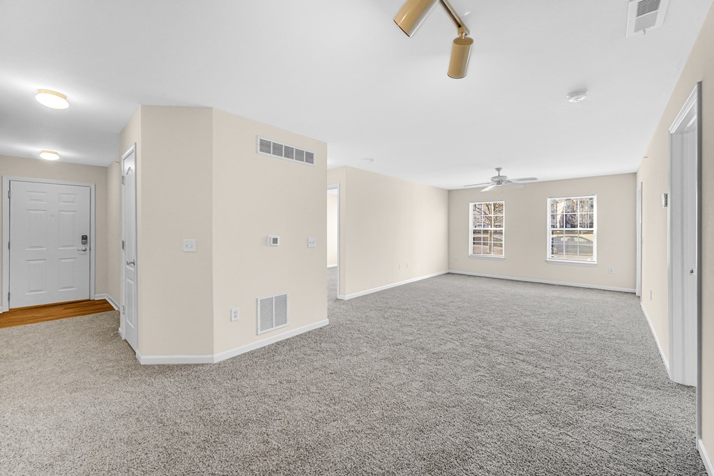 an empty living room with a ceiling fan and a door at Brickshire Apartments in Merrillville, IN 46410