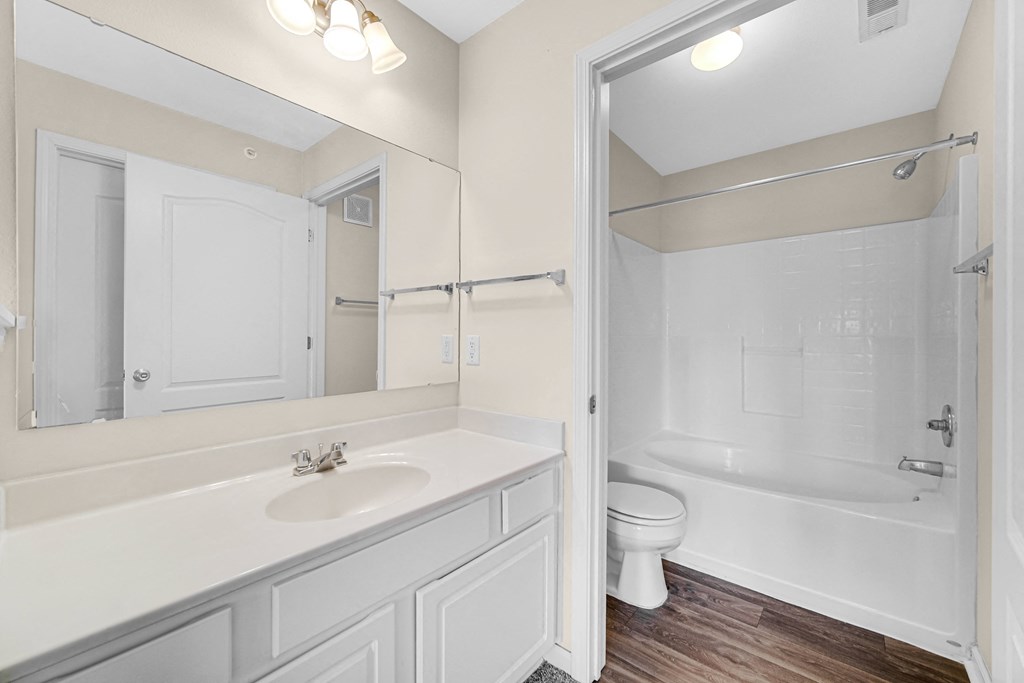 a bathroom with a mirror and a toilet and a sink at Brickshire Apartments in Merrillville, IN 46410