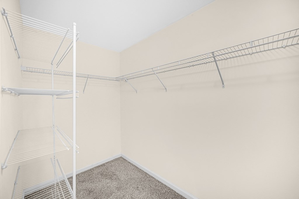 a spacious closet with white walls and shelves and a mirrored closet rack on the wall at Brickshire Apartments in Merrillville, IN 46410