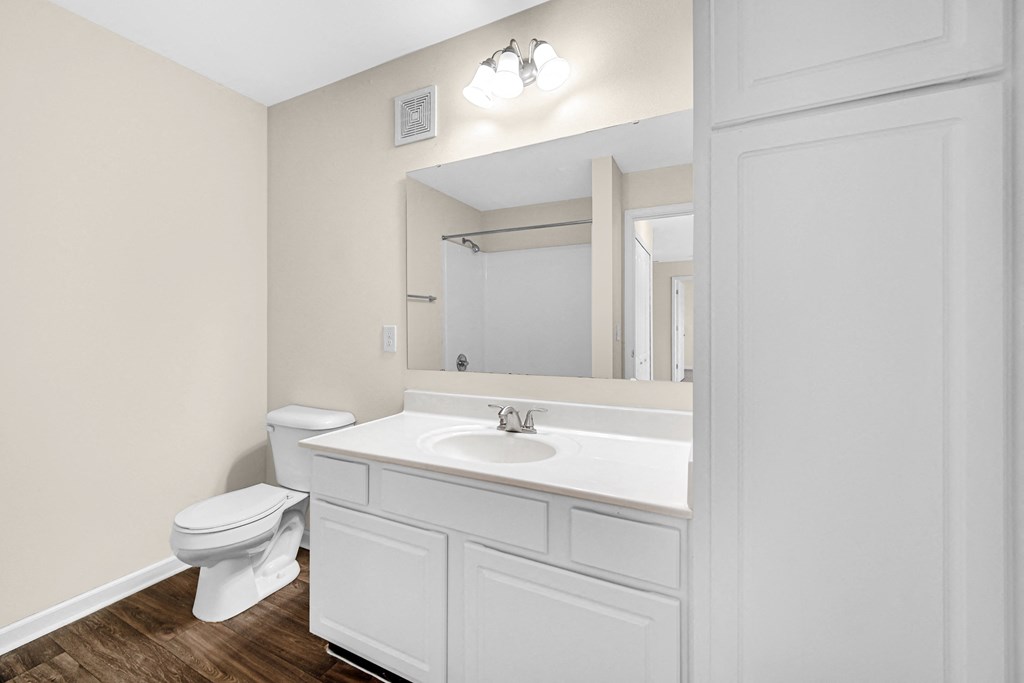 a bathroom with a sink and a toilet and a mirror at Brickshire Apartments in Merrillville, IN 46410