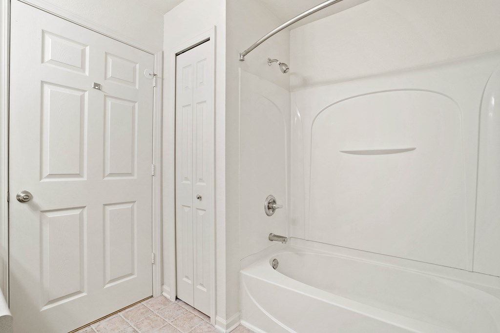 A white bathroom with a tub and a door.