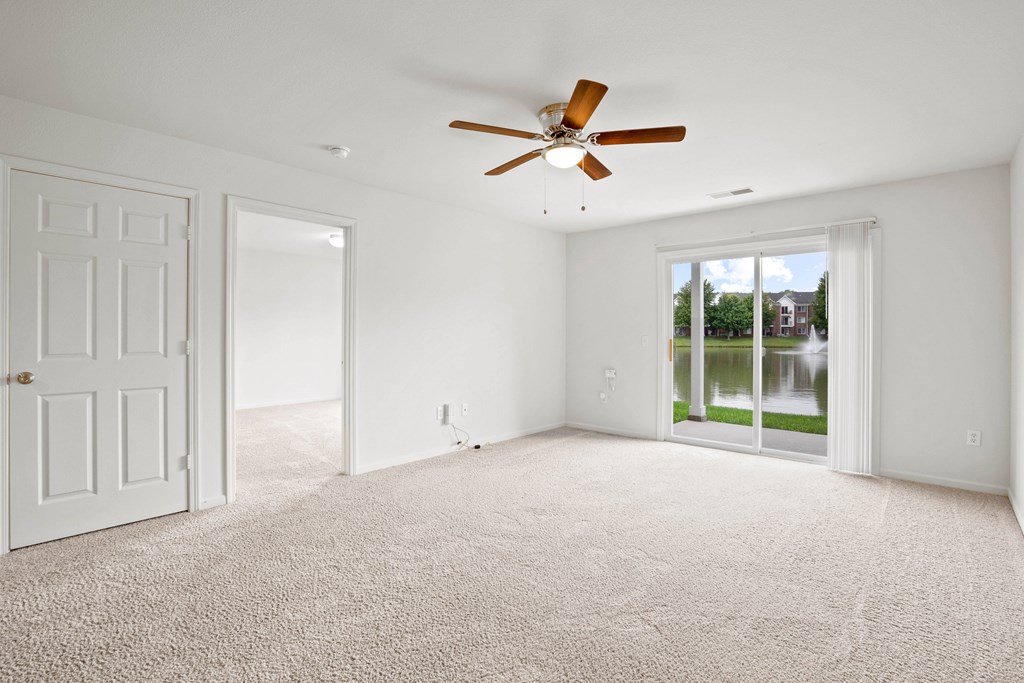 A room with a ceiling fan and carpeted floor.