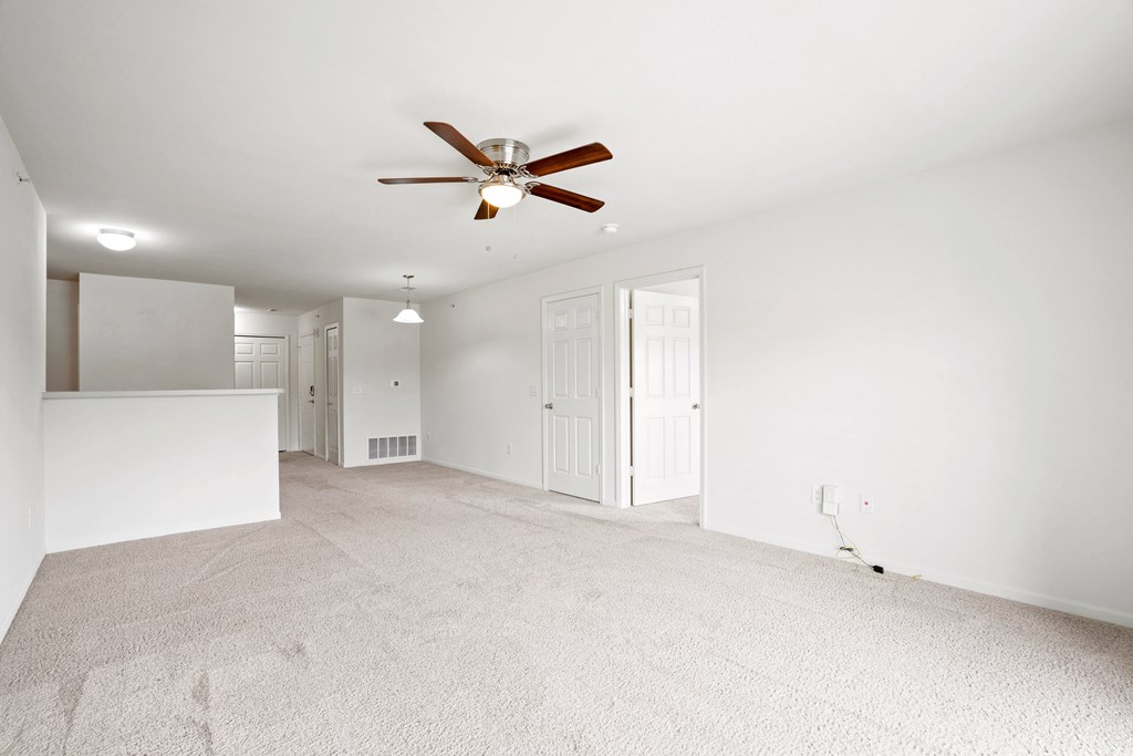 A room with a ceiling fan and carpeted floor.