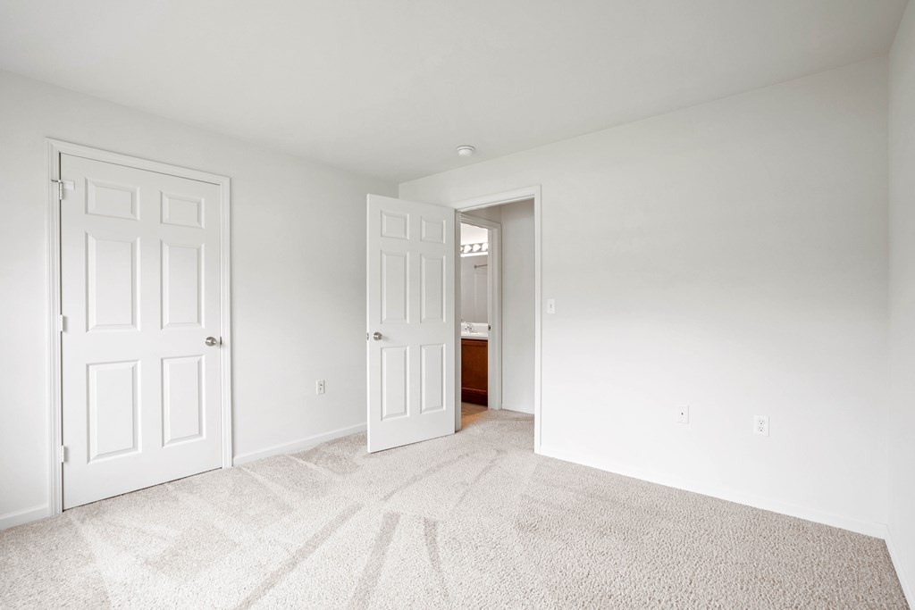 A white room with two doors and a carpet.