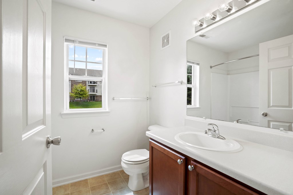 A white bathroom with a toilet, sink, and mirror.