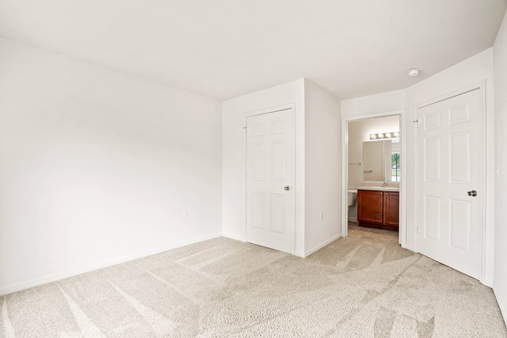 A room with a carpeted floor and two doors.