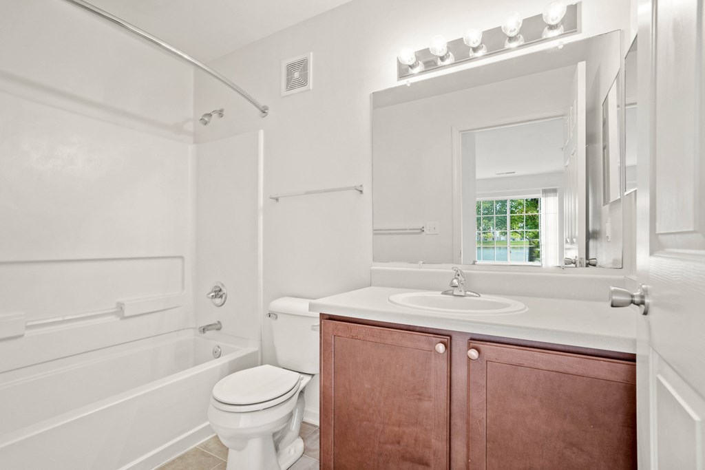 A white bathroom with a toilet, sink, and mirror.