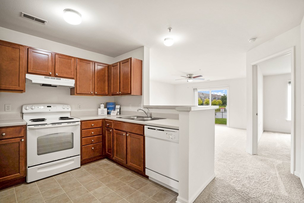 A kitchen with white appliances and brown cabinets.