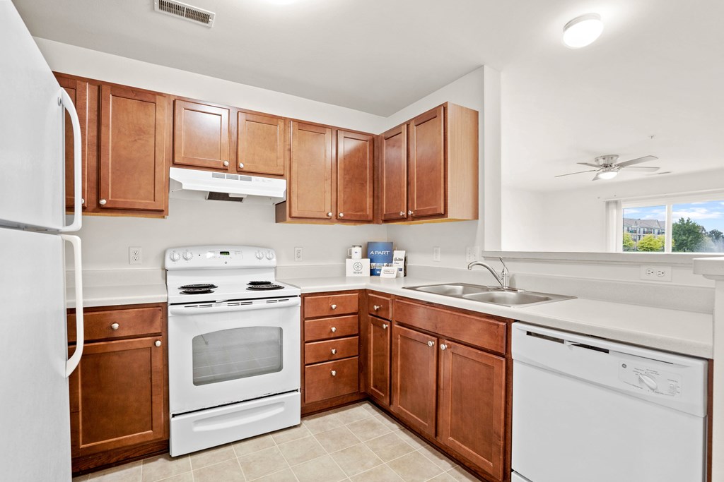 A kitchen with white appliances and wooden cabinets.