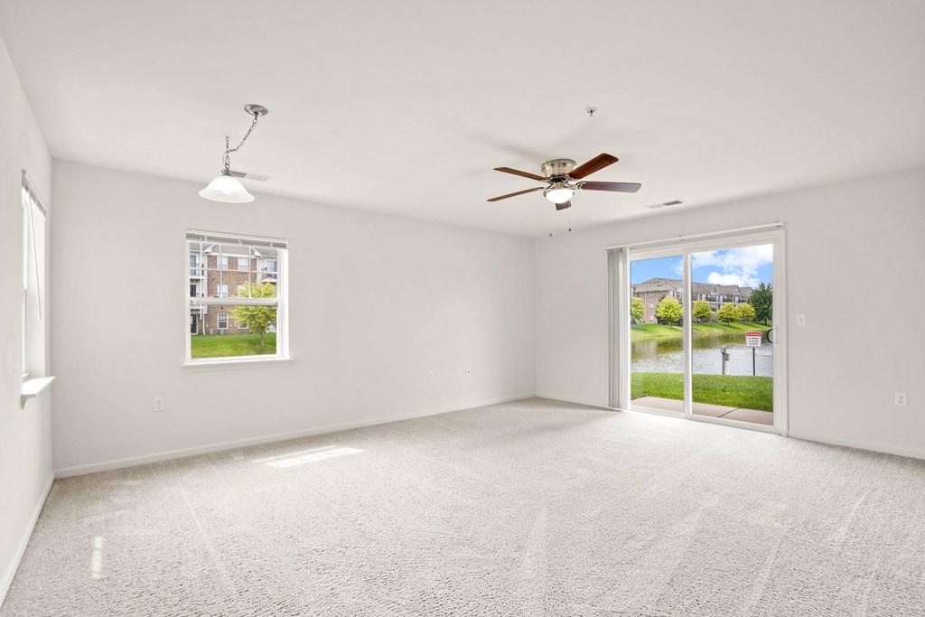 A spacious room with a ceiling fan and a view of the outdoors through a sliding glass door.