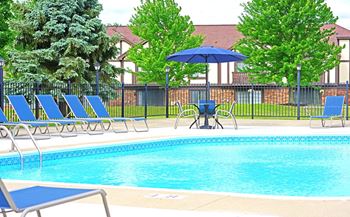 A pool with blue chairs and a black fence.