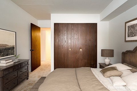 A bedroom with a large bed, a dresser, and a painting on the wall at Beacon Hill and Great Oaks Apartments, Rockford, Illinois