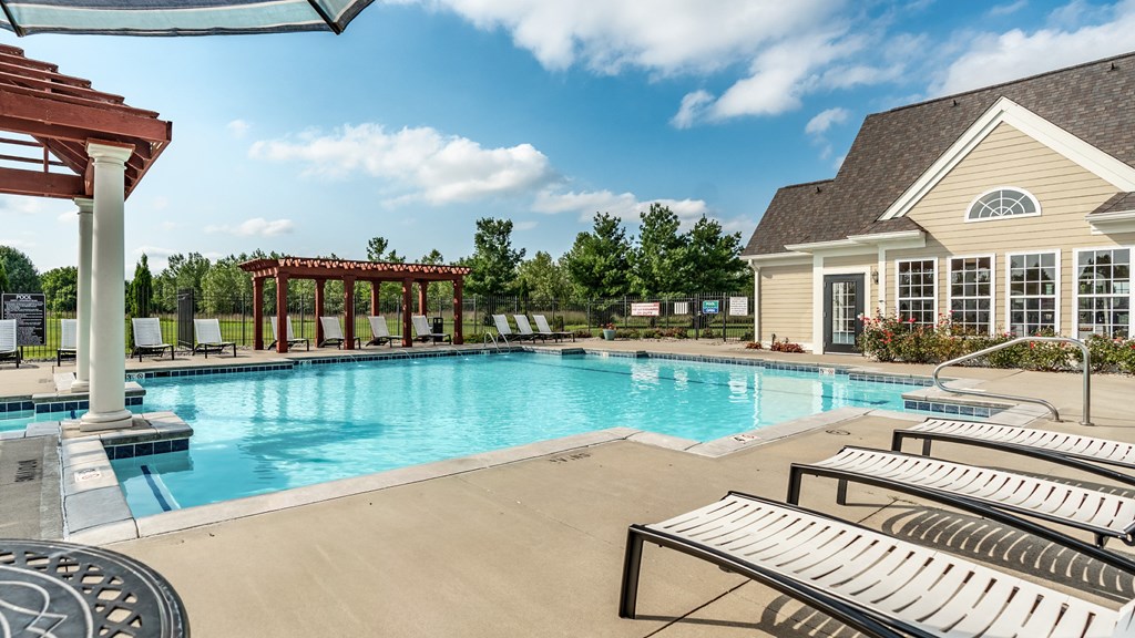 A pool area with sun loungers and a pavilion