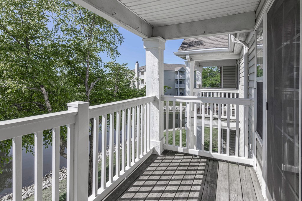 a porch with a white railing and a house in the background at Latitudes Apartments, Indianapolis