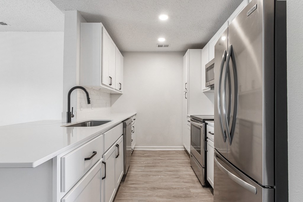 an empty kitchen with white cabinets and stainless steel appliances at Latitudes Apartments, Indiana