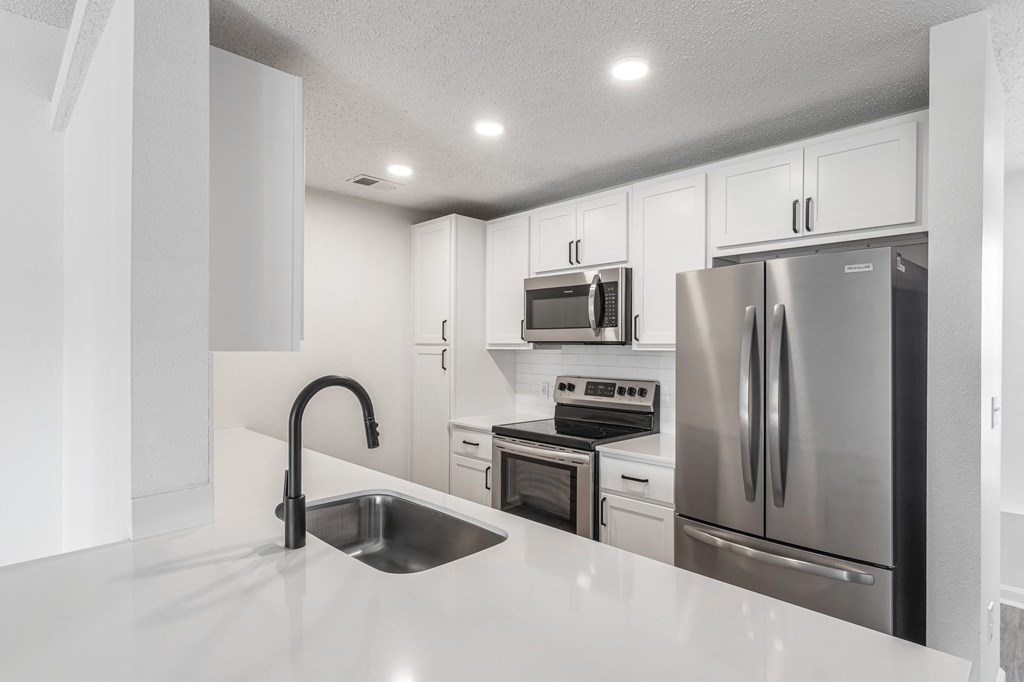 a kitchen with white cabinets and stainless steel appliances at Latitudes Apartments, Indiana, 46237