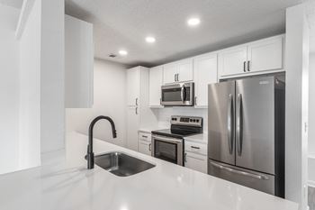 a kitchen with white cabinets and stainless steel appliances at Latitudes Apartments, Indianapolis, IN