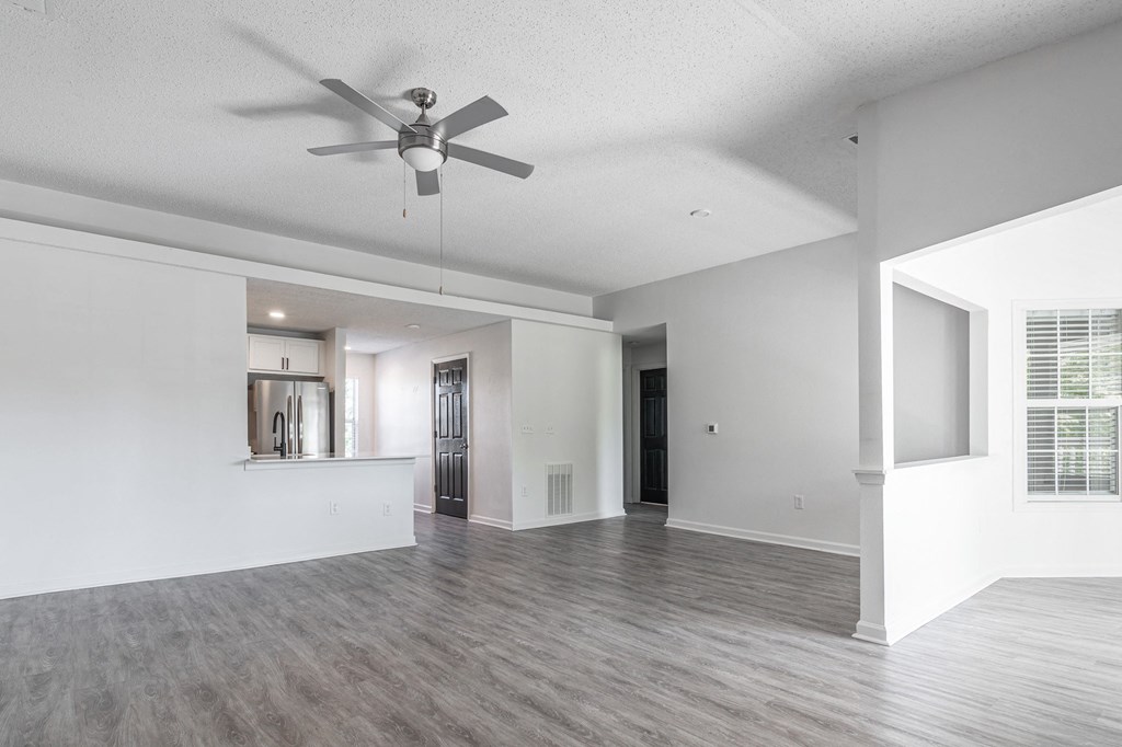 an empty living room and kitchen with a ceiling fan at Latitudes Apartments, Indiana