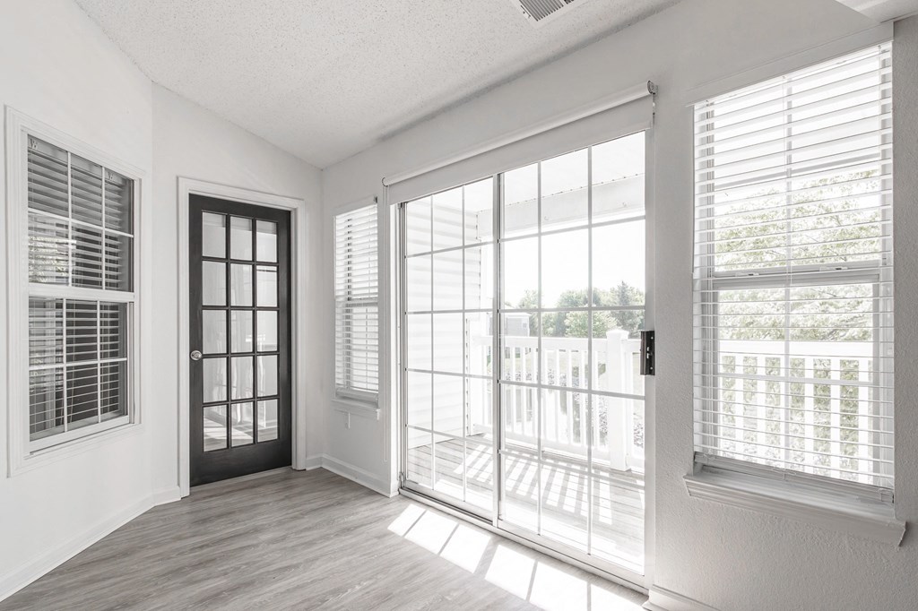 an empty living room with large windows and a door to a balcony at Latitudes Apartments, Indianapolis