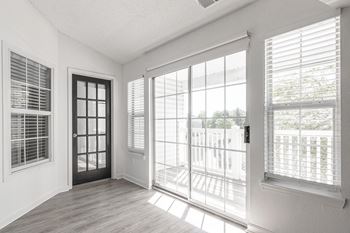 an empty living room with large windows and a door to a balcony at Latitudes Apartments, Indianapolis, Indiana