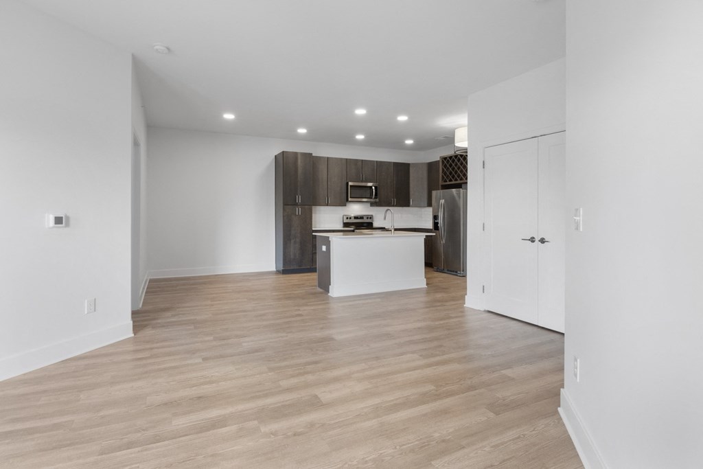 an empty living room and kitchen with white walls and wood flooring in Carmel, IN, 46032