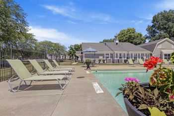 A pool area with sun loungers and a building in the background at Bay Pointe Apartments, Lafayette, IN