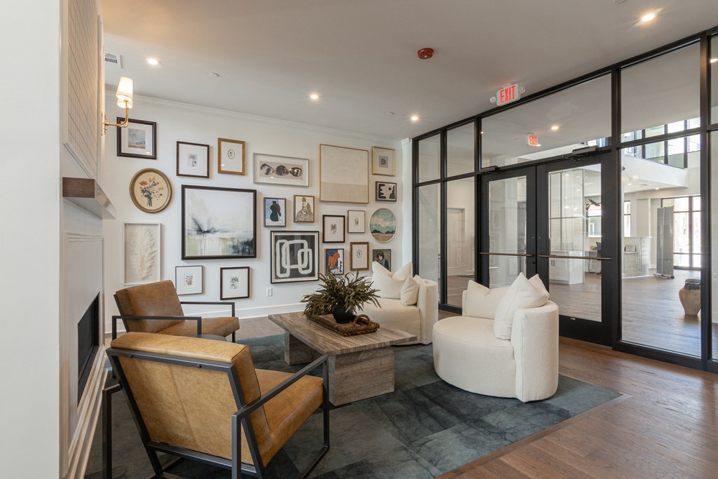 a living room with white furniture and a wall of framed pictures