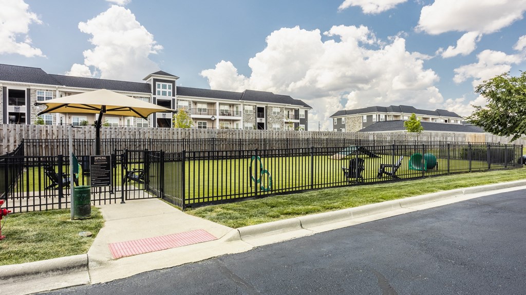 a fenced in yard with a playground and apartments in the background at The Avenue at Polaris Apartments, Columbus, OH