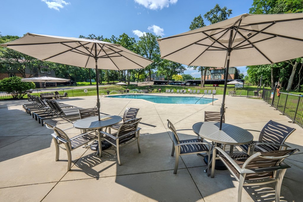 A poolside area with tables and chairs and umbrellas