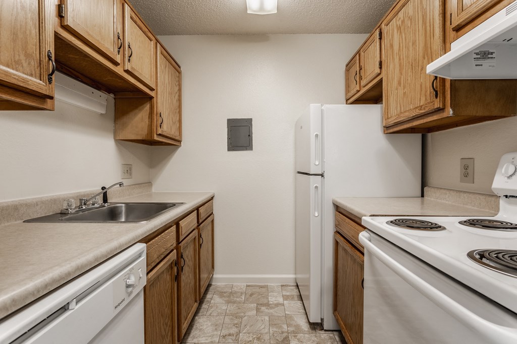 a kitchen with wooden cabinets and white appliances at Bavarian Village Apartments, Indianapolis