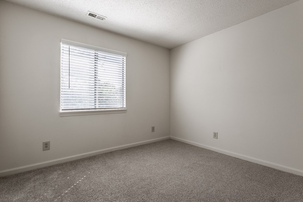 a bedroom with white walls and carpeted flooring and a window at Bavarian Village Apartments, Indianapolis, Indiana