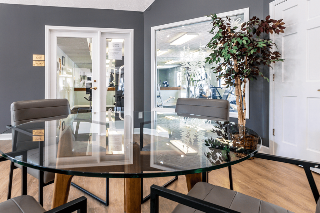 a dining room with a glass table and four chairs at Bavarian Village Apartments, Indianapolis