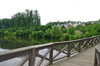 a wooden bridge over a body of water with trees in the background  at Enclave Apartments, Midlothian, 23114