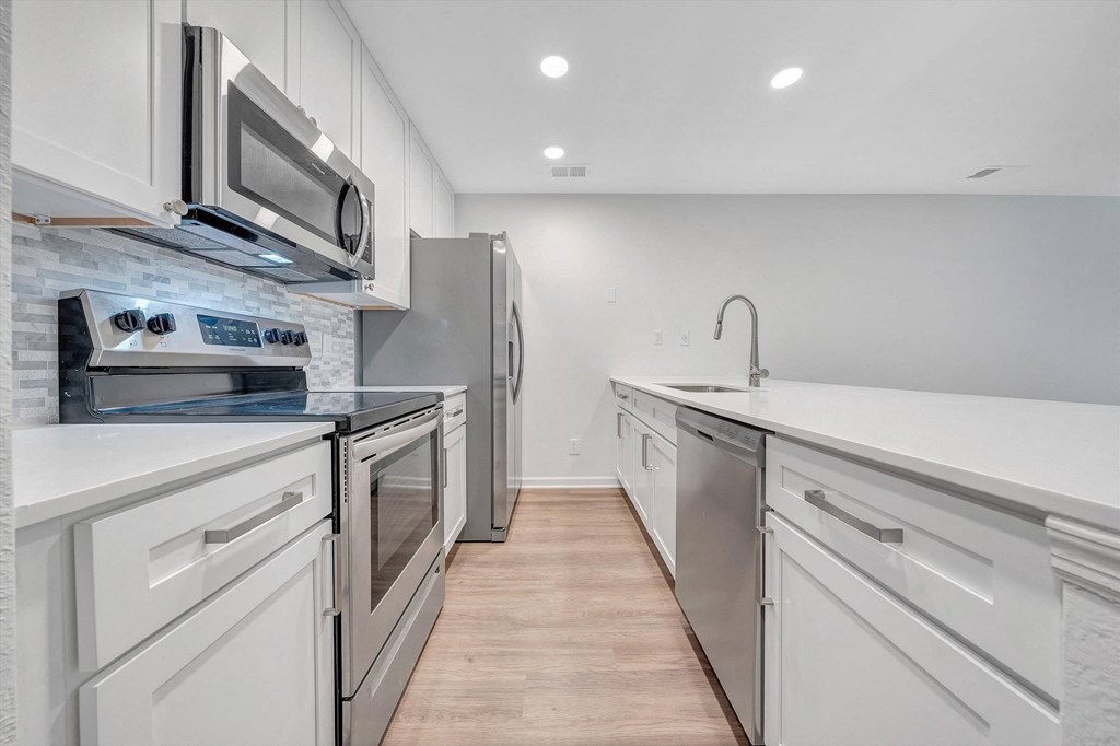 a kitchen with white cabinets and stainless steel appliances at The Vinings Apartments, Richmond