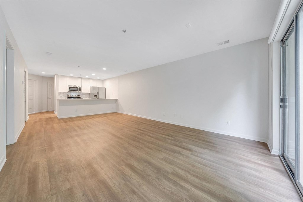 a bedroom with a medium sized bed and a kitchen in the background  at The Vinings Apartments, Virginia