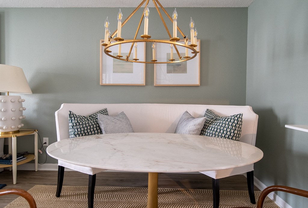 a round marble table with pillows on it under a brass chandelier  at The Vinings Apartments, Richmond