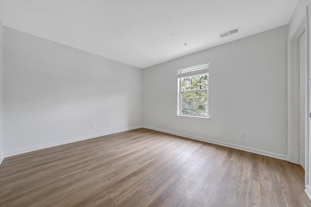 a bedroom with white walls and hardwood floors at The Vinings Apartments, Richmond, VA