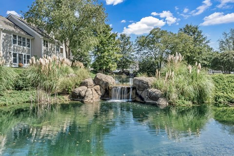 a pond with a waterfall in front of a house at Trophy Club at Bellgrade, Midlothian, VA, 23113