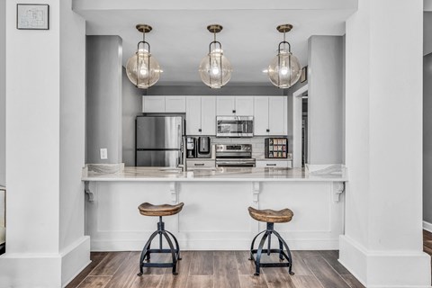 a kitchen with white cabinets and a bar with two stools at Trophy Club at Bellgrade, Midlothian, VA, 23113