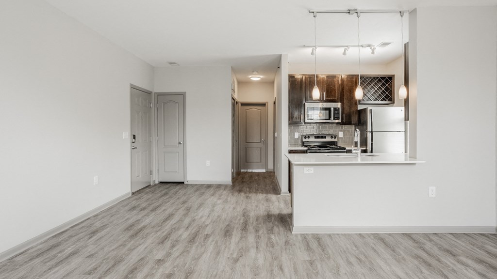 an empty living room and kitchen with white walls and wood flooring at The Avenue at Polaris Apartments, Columbus, OH