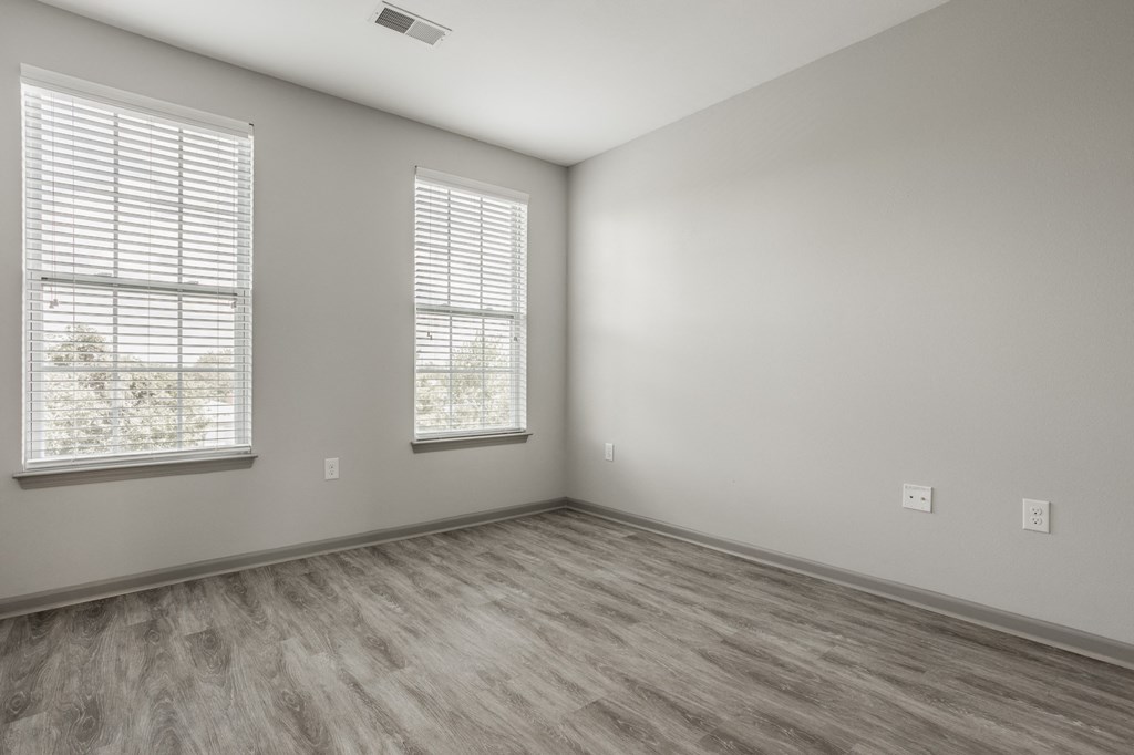 an empty room with wood flooring and two windows at The Avenue at Polaris Apartments, Columbus, OH