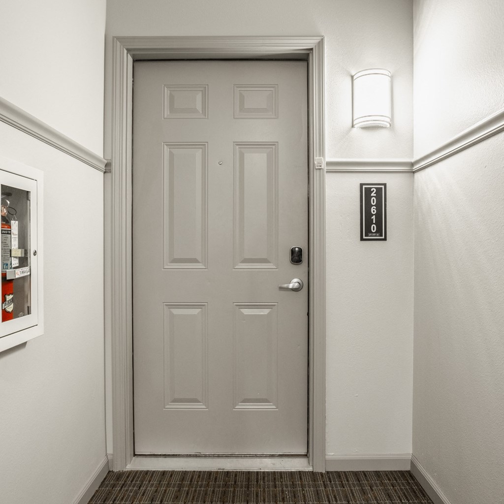 a white door in a hallway with a white wall and a door knob at The Avenue at Polaris Apartments, Columbus, OH