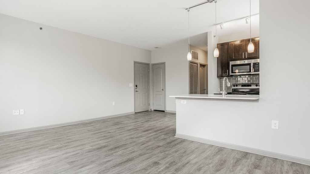 a living room with a white wall and a kitchen at The Avenue at Polaris Apartments, Columbus, OH