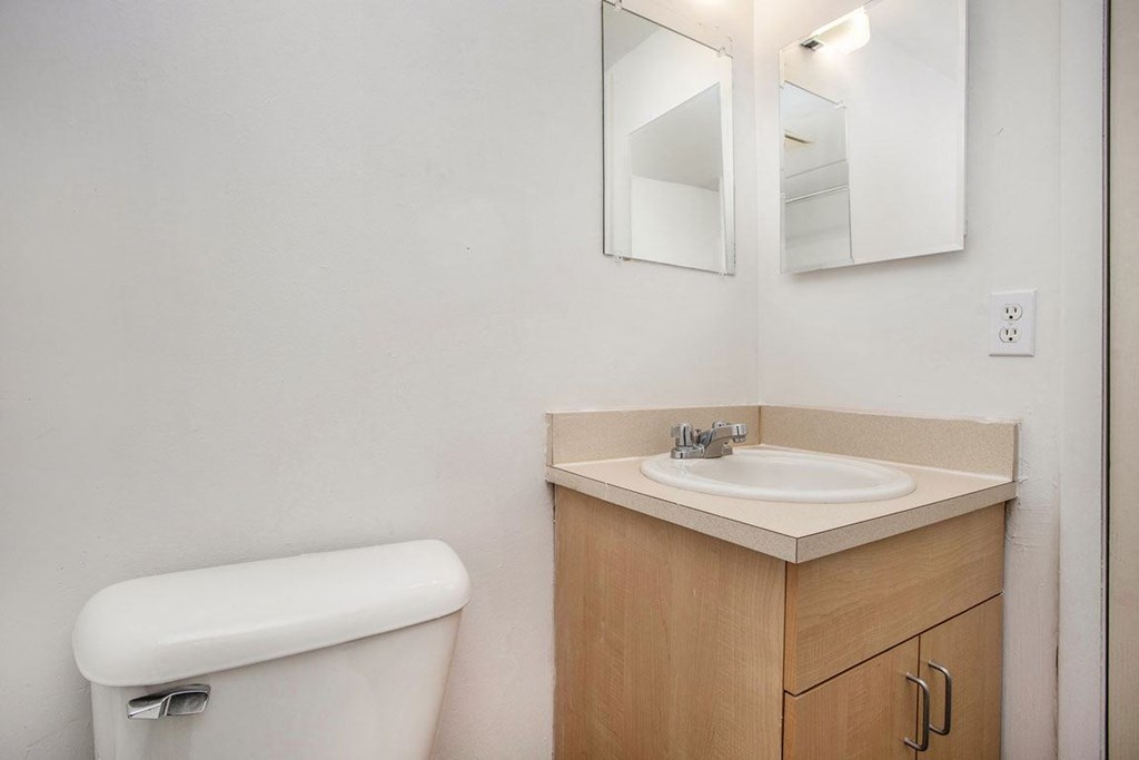 a bathroom with a sink and a toilet and a mirror at Fairlane Apartments in Springfield, MI