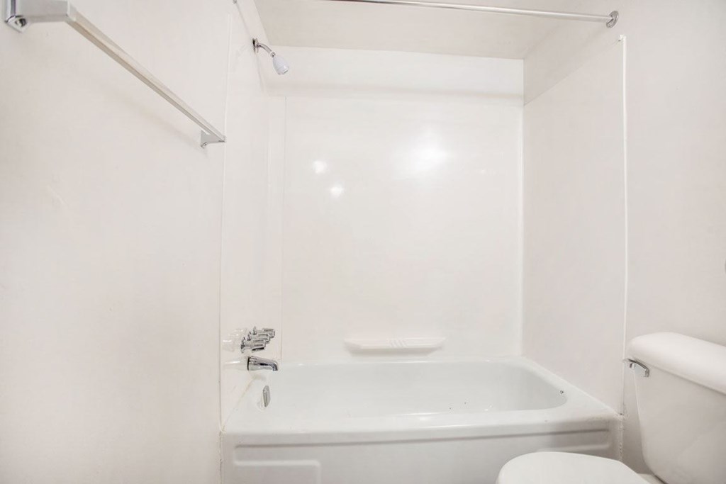 a white bathroom with a tub and a toilet at Fairlane Apartments in Springfield, MI
