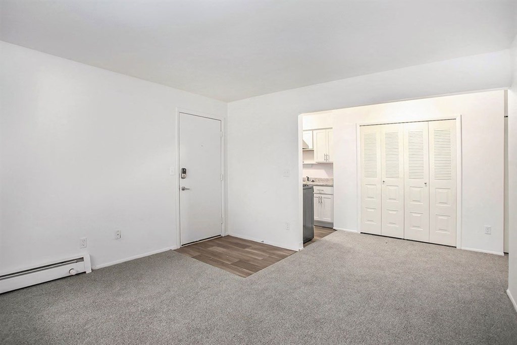 an empty living room with a kitchen in the background at Fairlane Apartments in Springfield, MI