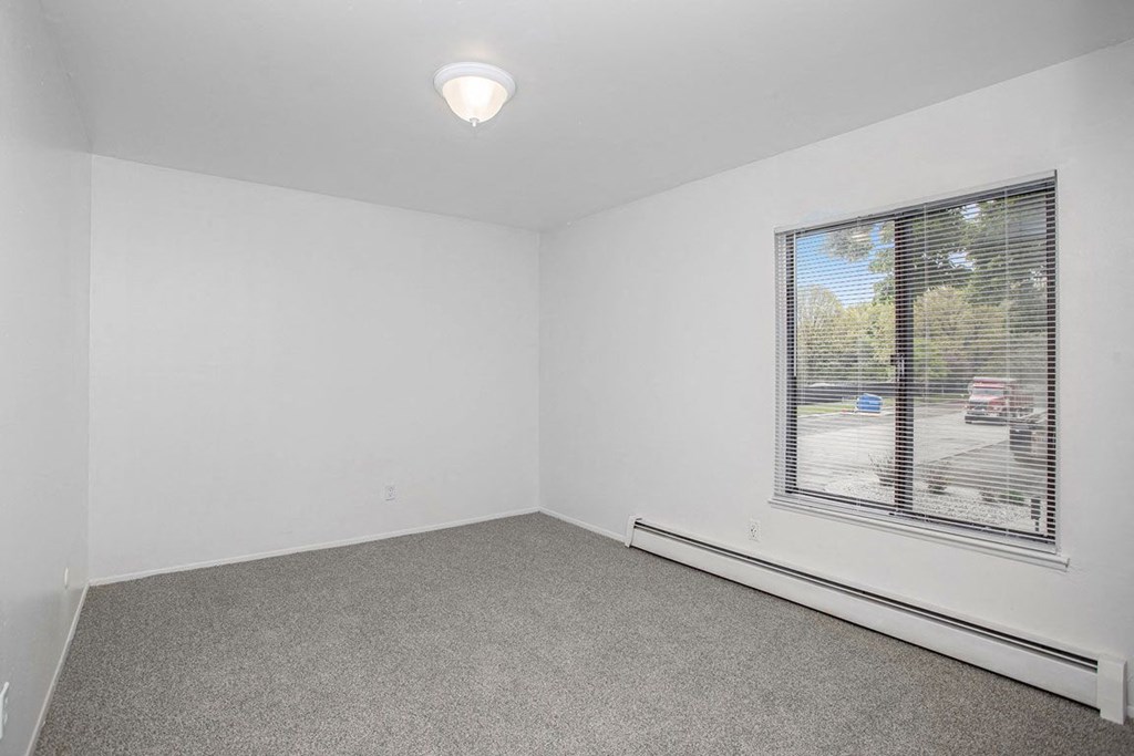 an empty bedroom with a large window at Fairlane Apartments in Springfield, MI